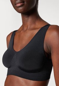 Black seamless bralette with a deep V-neckline, wide straps, and a textured underband. Fabric appears smooth and stretchy.