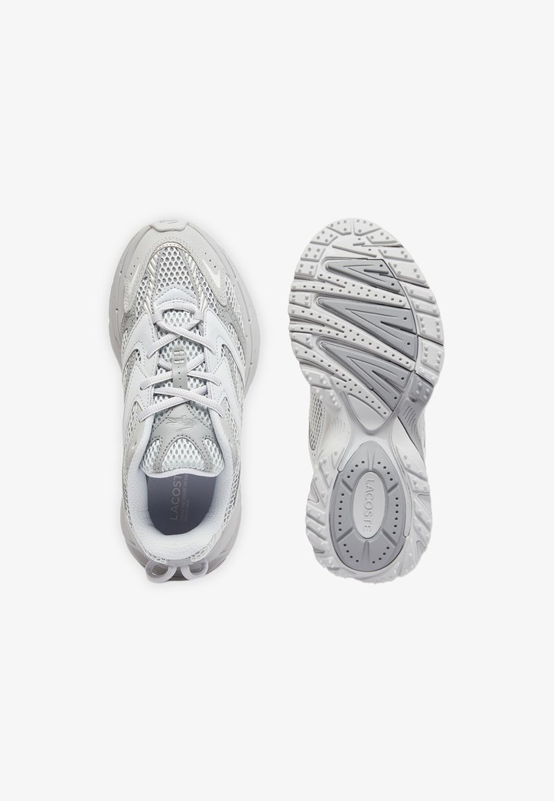 Scarpe da ginnastica bianche in mesh e pelle, una vista dall'alto con i lacci, l'altra che mostra la suola texturizzata con il nome del marchio Lacoste.