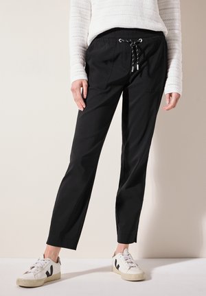 Pantaloni jogger neri con vestibilità rilassata, vita elasticizzata e chiusura con cordino. Presentano due tasche frontali e orli cuffati.