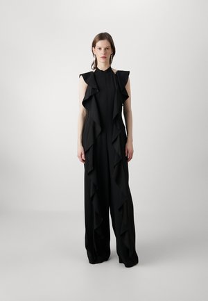 Black jumpsuit featuring ruffled drapes along the front, sleeveless design, and wide-leg trousers, made from a lightweight fabric.