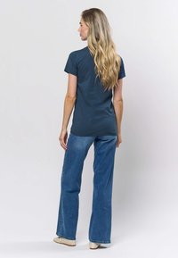 Tamnoplava pamučna majica uskog kroja, kratkih rukava i okruglog izreza, uparen s svijetloplavim širokim trapericama.