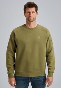 Sweatshirt vert olive avec un col rond côtelé, des manches raglan et une petite étiquette logo sur la poitrine ; texture lisse avec une coupe décontractée.