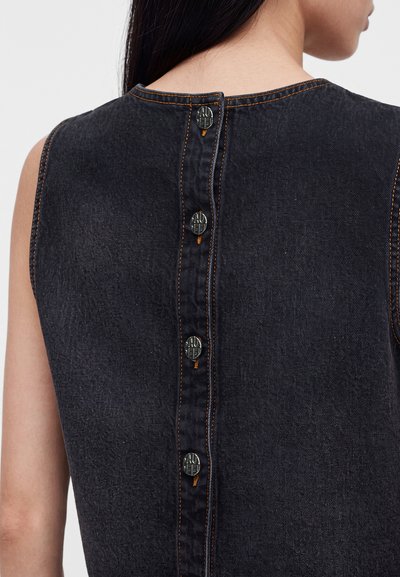 Vue arrière d'une robe sans manches en denim foncé avec quatre boutons noirs alignés verticalement le long de la couture centrale au dos.