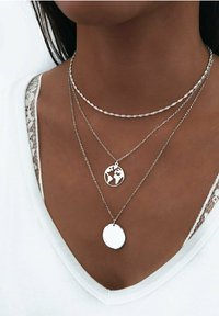 Collares en capas de plata que presentan un colgante en forma de globo y un colgante circular liso, con una cadena retorcida texturizada y eslabones delicados.
