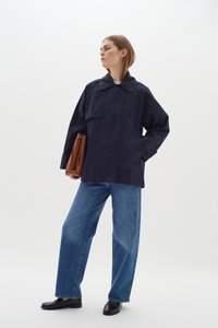 Jūras zilā ūdensnecaurlaidīgā jaka ar lielu apkakli, divām priekšējām kabatām un pogām. Saskaņota ar gaiši ziliem platām kājām džinsiem un melniem apaviem.