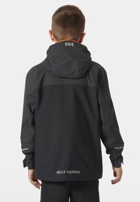 Czarna wodoodporna kurtka z kapturem, odblaskowe akcenty na rękawach oraz branding "HELly HANSEN" na dolnej części pleców. Gładka tekstura.