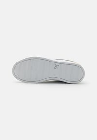 Suela de zapato con una suela de goma blanca texturizada con ranuras horizontales y un logo grabado cerca del talón. Diseño duradero y antideslizante.