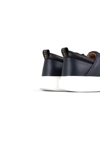 Sneakers in pelle blu navy con suola in gomma bianca. Le caratteristiche includono un retro arrotondato, colletto imbottito nero e branding dorato sulla linguetta del tallone.