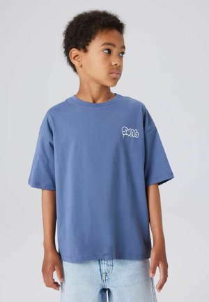 Blue cotton t-shirt with a crew neck, loose fit, and short sleeves. Features a white graphic text "SWAG" on the left chest area.
