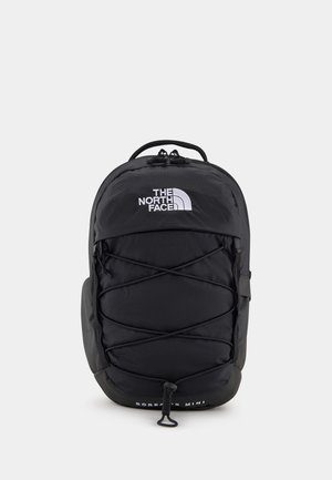 Petit sac à dos Borealis Mini noir de North Face avec cordons élastiques avant et fermeture éclair supérieure, présenté sur un fond clair uni.