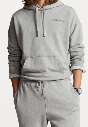 Sweat à capuche gris en mélange de coton avec une poche kangourou, une capuche à cordon de serrage et un logo brodé. Associé à un pantalon assorti avec des poches latérales.