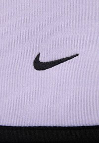 Tessuto viola con una finitura strutturata, caratterizzato dal logo Swoosh ricamato in nero della Nike. Cuciture nere sul bordo inferiore.