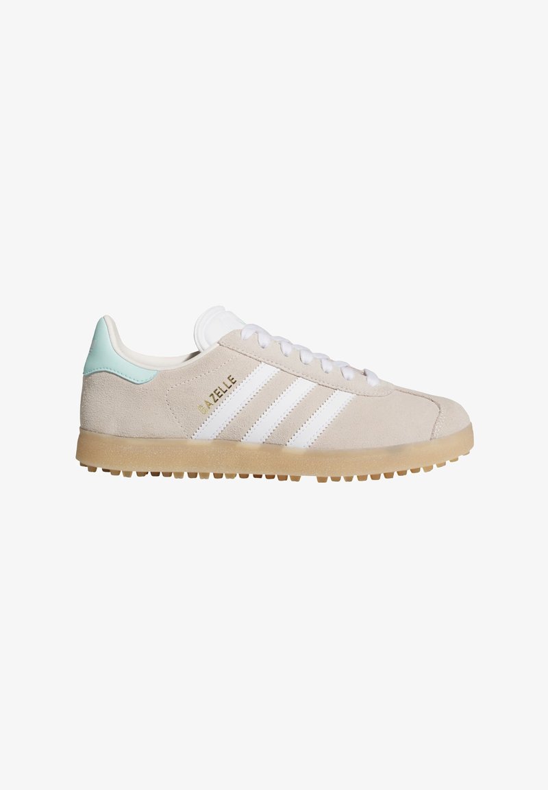 Μπεζ σουέντ αθλητικό παπούτσι Adidas Gazelle με λευκές ρίγες, σόλα από καουτσούκ, πράσινη μυρωδιά φτέρνας και λευκά κορδόνια, εμφανίζεται σε πλάγια όψη.
