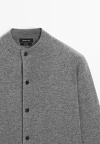 Grauer Wollcardigan mit Rundhalsausschnitt, ausgestattet mit einer Knopfleiste und gerippten Details am Kragen und den Bündchen. Glatte Textur.