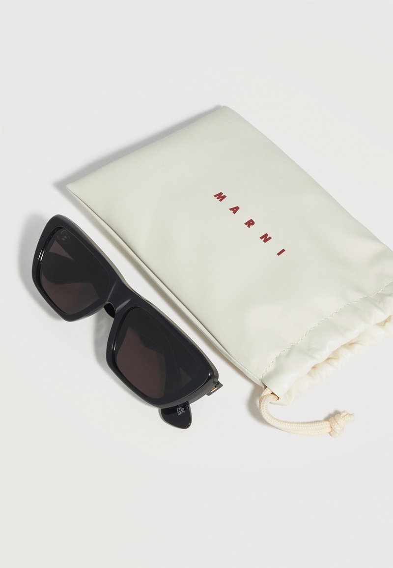 Black oversized rectangular sunglasses next to an off-white drawstring pouch with "MARNI" printed in red letters.