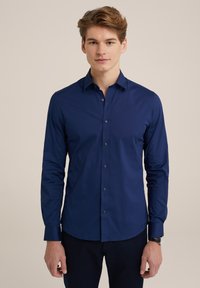 Cămășă albastru închis cu mânecă lungă, guler cu nasturi, nasturi în față și țesătură texturată. Caracteristici include un design ajustat și manșete cu detalii din nasturi.
