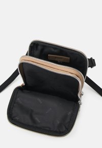 Borsa a tracolla nera in tessuto con zip bronzo, multiple tasche e un'etichetta testurizzata. Design compatto, fodera interna morbida.