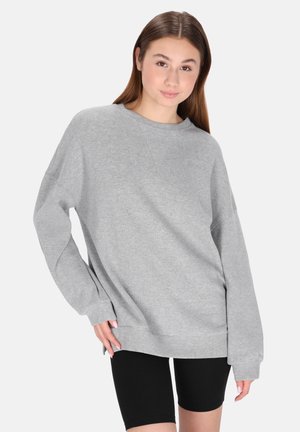 Felpa grigia, vestibilità morbida, colletto rotondo, maniche lunghe con orli a costina, realizzata in materiale morbido, abbinata a pantaloni corti neri.