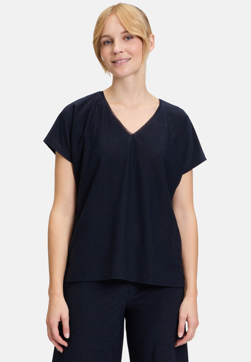 Schwarzes Kurzarmoberteil mit V-Ausschnitt, lockere Passform und glatter Textur, kombiniert mit passenden dunklen Hosen.