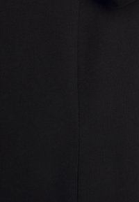 Gros plan d'un tissu côtelé noir montrant la texture tricotée et une couture verticale au centre.