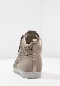 Beige mockaläders höga sneakers med nitar och metallisk häldel. Har en bakre dragkedja och en strukturerad gummisula.