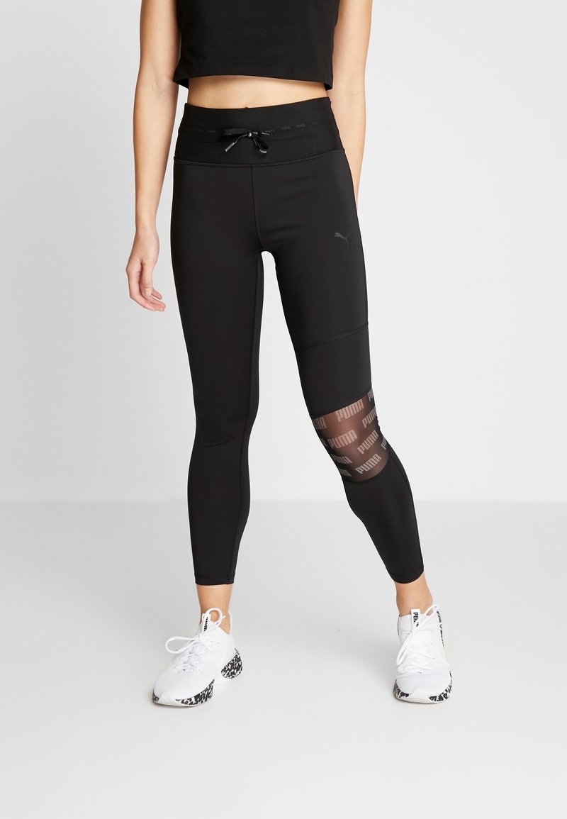 Leggings sportivi neri con vita alta, caratterizzati da un pannello in rete con dettagli logo. Il materiale è morbido, con un design semi-attillato.