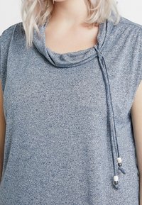 Modrá melírovaná halenka s kápovým výstřihem a nastavitelnými stahovacími šňůrkami se korálkovými akcenty. Měkká látka, krátké rukávy a volný střih.