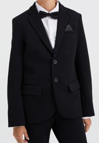 Svart texturerad blazer med två knappar, slagkrage och sidofickor. Matchad med en vit skjorta och en svart fluga. Accenterad med en fickruta.