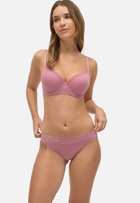 Bralette rosa con canalé, con aros y tirantes ajustables. Tanga a juego con borde de encaje y textura suave. Diseño minimalista.