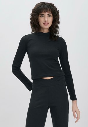 Zwarte lange mouwen crop top met een opstaande kraag en een uitsnijding aan de voorkant. De stof lijkt glad en rekbaar, geschikt voor sportkleding.
