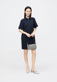 Ναυτικό φόρεμα κοντό μανίκι με φερμουάρ μπροστά, συνδυασμένο με τσάντα με σχέδια και ανο�ιχτό μπεζ τακούνια. Λείο ύφασμα, δομημένο σχέδιο.