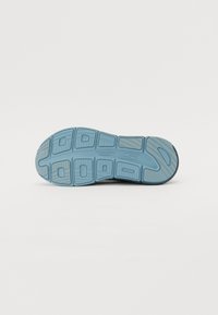Suela de zapatilla deportiva que presenta un caucho azul claro con surcos texturizados y secciones distintas para tracción y flexibilidad.
