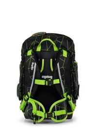 Zaino nero con motivo geometrico verde, spallacci regolabili e dettagli riflettenti. Presenta più tasche e un materiale resistente.