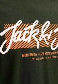 Donkergroene stoffen t-shirt met witte en oranje tekst. Het ontwerp bevat een gestreepte achtergrond met "Jack" in een cursieve schrift en extra details eronder.