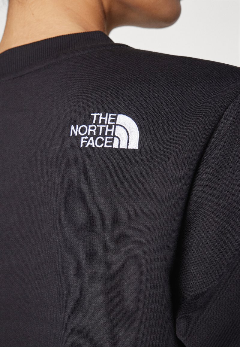 Zwarte sweatshirt met geribbelde kraag. Voorzien van een wit geborduurd logo van The North Face op de bovenrug, een eenvoudig en strak ontwerp.