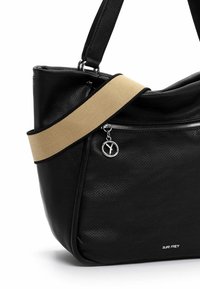 Sac à main en cuir noir perforé avec une large bandoulière en toile beige. Il est équipé d'une fermeture éclair argentée et d'un pendentif métallique circulaire avec un logo embossé.