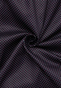 Tessuto blu navy con superficie texturizzata e piccoli pois rossi e blu, disposti uniformemente su tutta la materia.