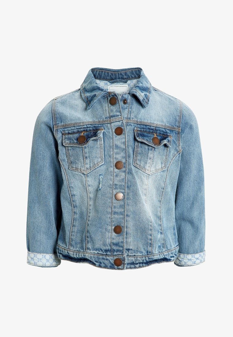 Veste en jean bleu clair avec boutons sur le devant, deux poches poitrine boutonnées et tissu à motifs visible sur les poignets repliés.