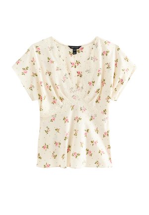 Blouse crème à manches courtes avec imprimé de roses roses et bordure en dentelle le long du décolleté en V profond et taille empire.