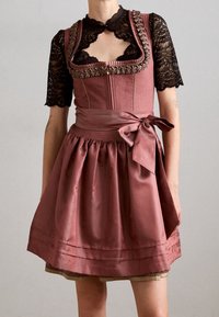 Femme portant une robe traditionnelle mauve avec des manches courtes en dentelle noire et un grand nœud noué à la taille.