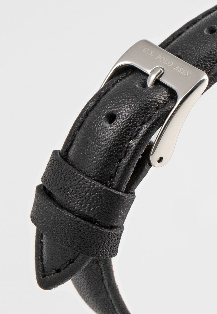 Schwarzes Lederarmband mit strukturierter Oberfläche, Metallschließe und geprägt Logo der Marke. Verfügt über mehrere Einstelllöcher zur Anpassung.