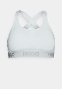 Lichtgrijze sportbeha gemaakt van zachte stof met kruisbanden en een brede band met het woord "HUGO" in zilveren letters.