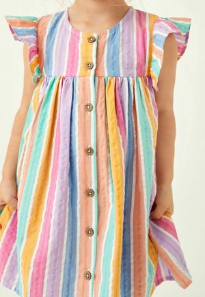 Enfant portant une robe sans manches à rayures verticales multicolores, avec des épaules volantées et des boutons en bois à l'avant.