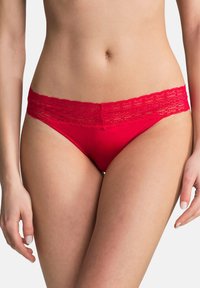 String rouge avec des bordures en dentelle, présentant un corps en tissu doux et une taille en dentelle délicate. Design minimaliste sans motifs supplémentaires.