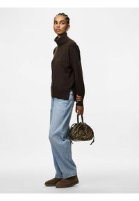 Maglione beige a collo alto, jeans azzurri a vita alta dal taglio morbido, stivaletti alla caviglia in suede marrone e una piccola borsa leopardata. Texture liscia, design casual.