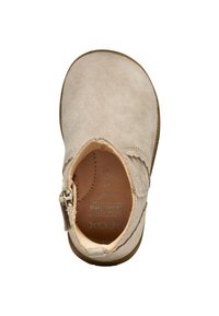 Zapato de ante beige con punta redondeada, cremallera lateral y interior de cuero suave. Presenta costuras sutiles y una suela de goma flexible.