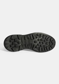 Zwarte rubberen zool met diepe gripgroeven en een versterkte hak. Bevat hoekige patronen en een glad oppervlak voor duurzaamheid.