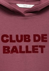 Bordový mikina s texturovanými, sametovými červenými písmeny nápisu "CLUB DE BALLET". Tkanina vypadá hladce s mírnou pružností.