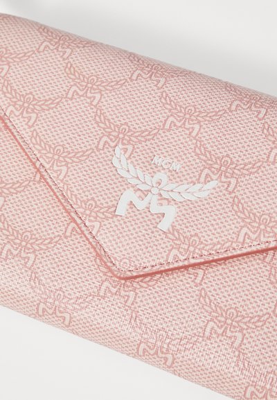 Heled roosa rahakott, millel on embosseeritud logo ja muster, tekstureeritud pind, ümbrikulaadne klapp ning valged õmblused.