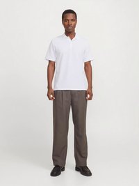 Polo blanc à manches courtes avec col, associé à un pantalon gris à jambes larges. Des chaussures noires complètent la tenue.